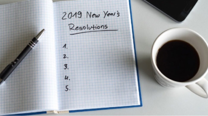 2019 new year's resolutions notebook, a cup of coffee and a pen